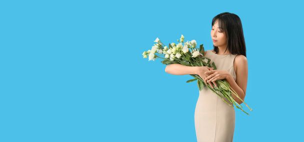 Hermosa mujer asiática sosteniendo ramo de flores de eustoma sobre fondo azul claro con espacio para texto - Foto, Imagen