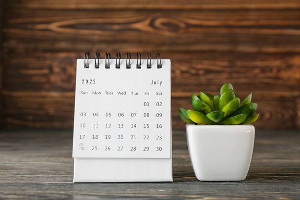 Flip paper calendar for July and houseplant on table, closeup - Valokuva, kuva