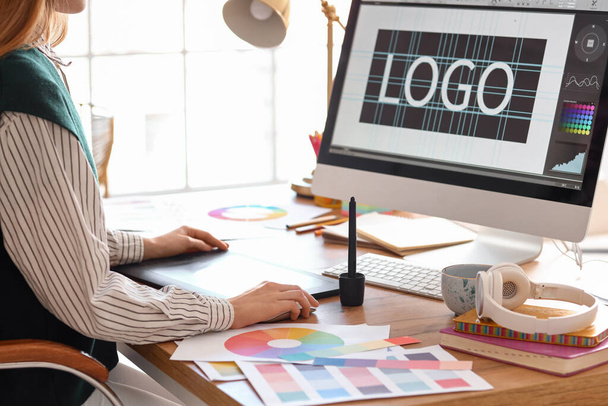 Женщина графический дизайнер работает с планшетом за столом в офисе, крупным планом - Фото, изображение