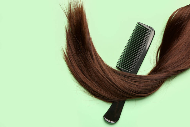Brown hair with comb on green background - Foto, afbeelding