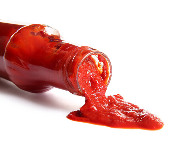 Ketchup spilled out of glass bottle on white background - Photo, Image