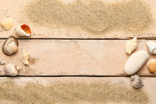 Sand with shells and stone on beige wooden background - Valokuva, kuva
