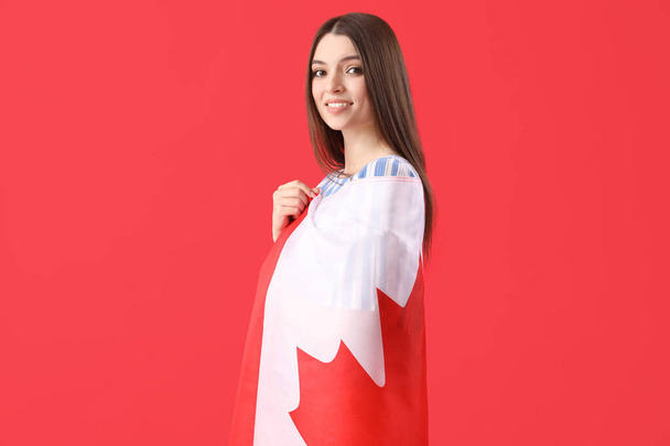 Kırmızı arka planda Kanada bayrağı olan genç bir kadın - Fotoğraf, Görsel