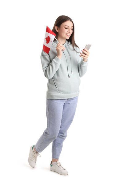 Young woman with flag of Canada using mobile phone on white background - 写真・画像