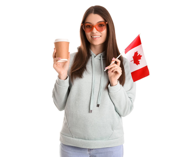 Kanada bayrağı ve beyaz arka planda bir fincan kahvesi olan genç bir kadın. - Fotoğraf, Görsel