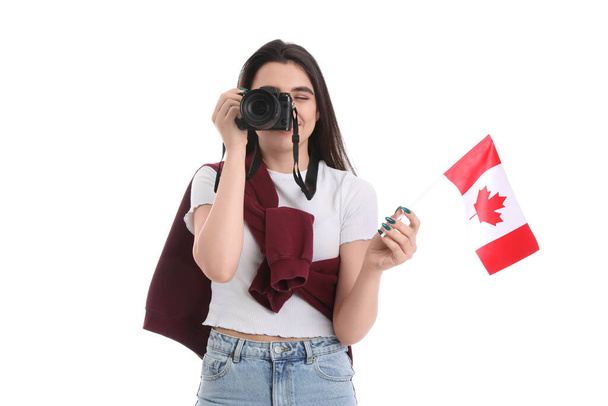 Νεαρή γυναίκα με φωτογραφική μηχανή φωτογραφία και σημαία του Καναδά σε λευκό φόντο - Φωτογραφία, εικόνα