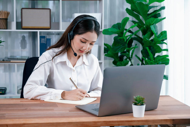 Azjatyckie call center z słuchawkami i mikrofonem pracujące na jej laptopie. Kobieta operator zapewniają wyjątkową obsługę klienta. Wspierający agent call center pomagający klientowi w dochodzeniu. Entuzjastycznie - Zdjęcie, obraz