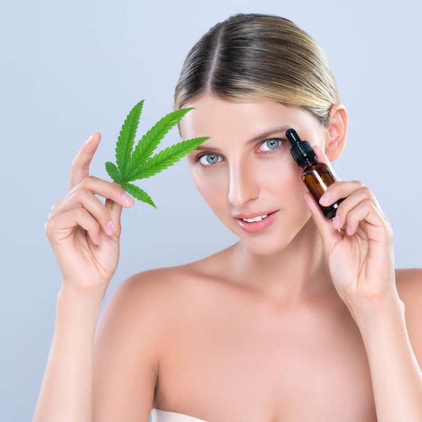 Alluring portrait of beautiful woman in isolated holding green leaf with marijuan extracted bottle for skincare treatment product. Cannabis CBD oil for cosmetology and beauty concept. - Fotoğraf, Görsel