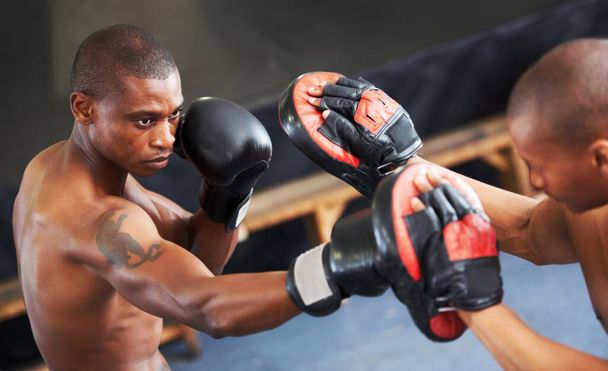 Motiváljuk egymást. Egy fókuszált fiatal bokszoló, aki védőruhás társával küzd. - Fotó, kép