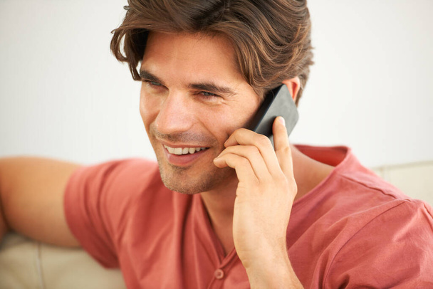 Using wireless technology to stay connected. A handsome young man talking to someone on his cellphone - Photo, image