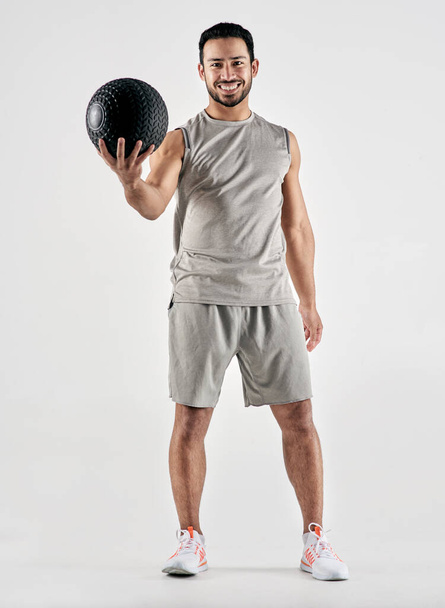 You might hate doing it, but youll love finishing it. Studio portrait of a muscular young man holding an exercise ball against a white background - Fotografie, Obrázek