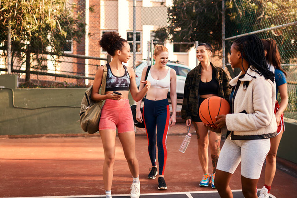Φίλοι που παίζουν μαζί, μένουν ενωμένοι. μια ποικιλόμορφη ομάδα φίλων ετοιμάζεται να παίξει ένα παιχνίδι μπάσκετ μαζί κατά τη διάρκεια της ημέρας - Φωτογραφία, εικόνα
