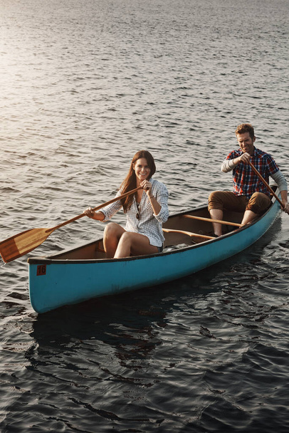 Enjoying their lakeside getaway. a young couple rowing a boat out on the lake - 写真・画像