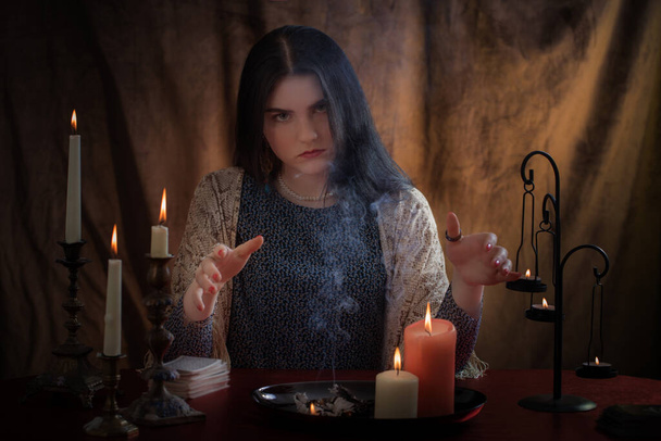 young witch conjures with burning candles on  dark background - Zdjęcie, obraz