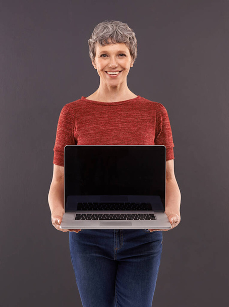 Esittelen uuden nettisivuni. Studio muotokuva iäkkäästä naisesta kannettava tietokone harmaata taustaa vasten - Valokuva, kuva