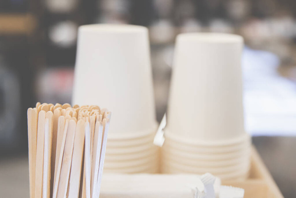 Background of paper cups and stirring sticks next to a coffee machine, cozy atmosphere of a coffee shop, selective soft focus - Φωτογραφία, εικόνα