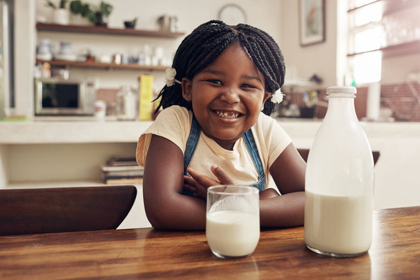 Kurabiyeler şu anda eksik olan tek şey. Evdeki mutfakta süt içen sevimli küçük bir kızın portresi. - Fotoğraf, Görsel
