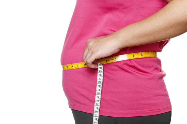Толстая женщина, измеряющая свой желудок, выделена на белом фоне. Избыточный вес, ожирение. Женский образ жизни - Фото, изображение