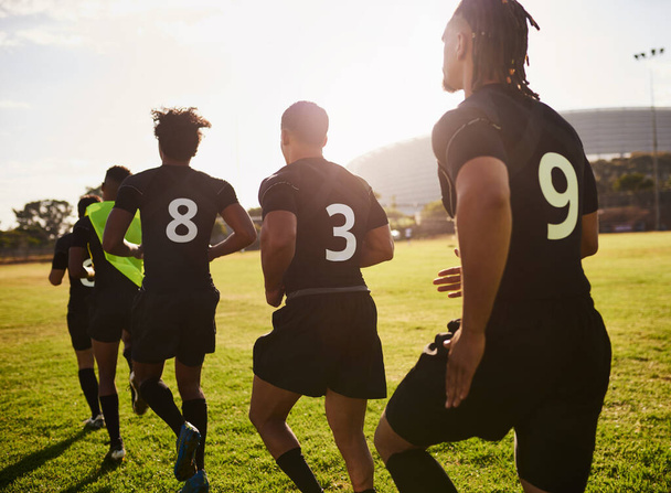 Correr nos mantiene en la cima de nuestro juego. un grupo irreconocible de deportistas que se calientan antes de jugar rugby durante el día - Foto, imagen