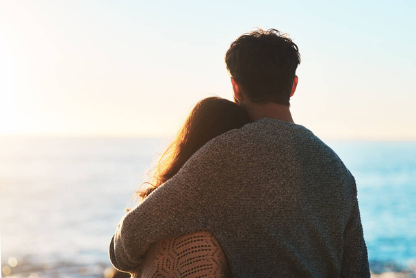 Любовь это величайшее приключение. Запись счастливой молодой пары, смотрящей на закат на пляже - Фото, изображение