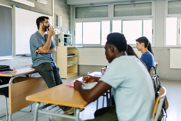 教室で男性教師の話を聞く学生。10代の高校生が大学で勉強する - 写真・画像