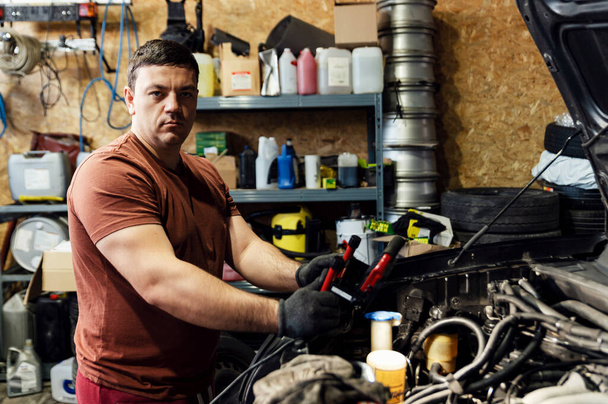 auto mechanic looks at the camera while working. SUV engine repair. fixing and fixing problems. quality repair. medium plan - Photo, Image