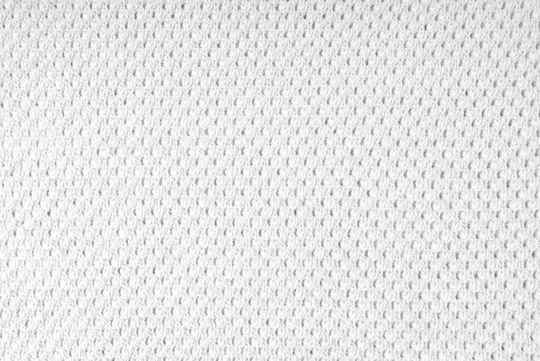Κοντινό πλάνο φόντο πλεκτό ύφασμα μαλλί με τελείες μοτίβο. Λευκή μάλλινη πλεκτή υφή. Ανοιχτή αφηρημένη πλεκτή φανέλα. Ύφασμα αφηρημένο φόντο - Φωτογραφία, εικόνα