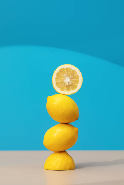 A pyramid of juicy yellow lemons on a blue background. Creative concept of fruits, citrus fruits. Healthy eating. - Valokuva, kuva