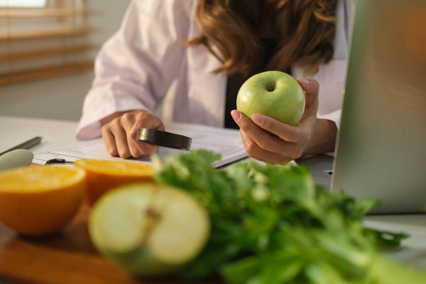 Táplálkozási, dietetikus dolgozik diéta séma és a laptop használata irodai pultnál. - Fotó, kép