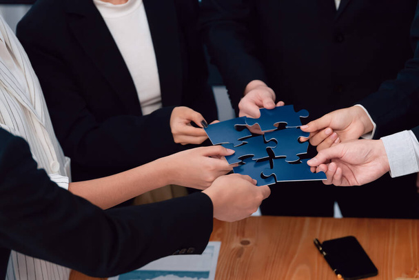 Closeup top view business team of office worker putting jigsaw puzzle together over table filled with financial report paper in workplace with manager to promote harmony concept in meeting room. - Fotoğraf, Görsel