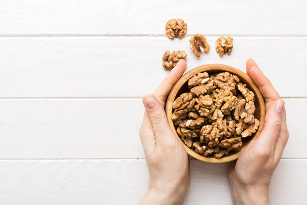 Woman hands holding a wooden bowl with walnut nuts. Healthy food and snack. Vegetarian snacks of different nuts. - Foto, imagen