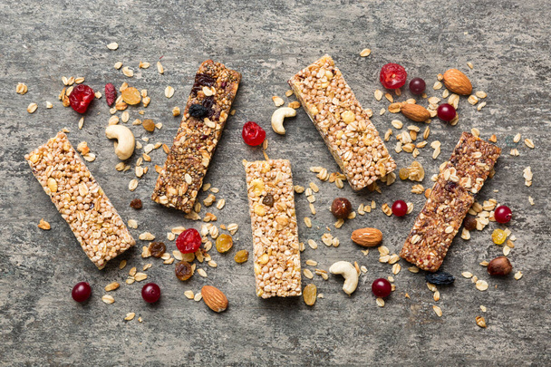 Various granola bars on table background. Cereal granola bars. Superfood breakfast bars with oats, nuts and berries, close up. Superfood concept. - Photo, Image