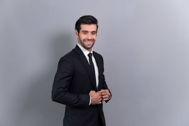 Stylish businessman in black suit posing confidently on isolated background, with a happy and optimistic smile as success and professionalism for businessman. Fervent - Photo, Image