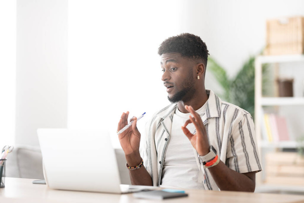 Młody, afrykański Amerykanin, ma rozmowę wideo na laptopie. Czarna osoba na żywo streaming lub rozmowy online. - Zdjęcie, obraz