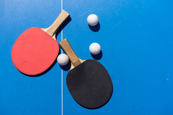 Tischtennisschläger und Bälle auf blauem Hintergrund, platzsparend, Sport und Hobby - Foto, Bild