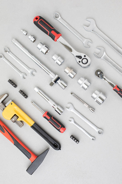 Комплект рабочих инструментов, молоток, плоскогубцы, отвертка, регулируемый гаечный ключ, розетки для ремонта на сером бетонном фоне. Плоский лежал - Фото, изображение