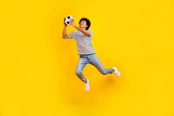 Full body length photo of young professional sportsman goalkeeper catch ball playing soccer jumping isolated on yellow color background. - Foto, immagini