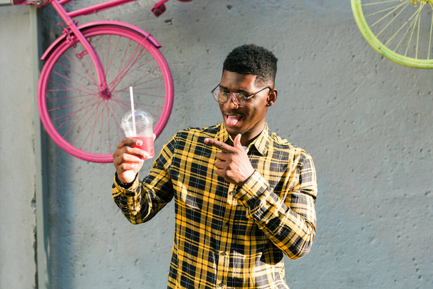 Giovane maschio afroamericano allegro sulla città divertendosi e tenendo cocktail. Uomo in vacanza estiva. Stile di vita per il tempo libero vacanza e bevande estive concetto. - Foto, immagini