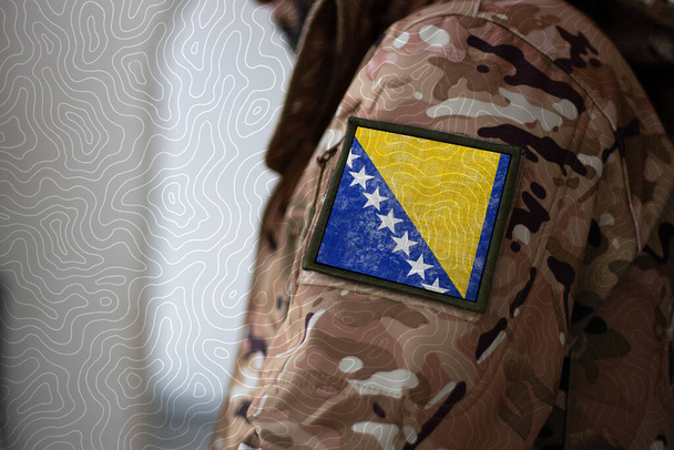 Soldado de Bosnia y Herzegovina. Soldado con bandera Bosnia y Herzegovina, bandera de Bosnia y Herzegovina con uniforme militar. Ropa de camuflaje - Foto, imagen