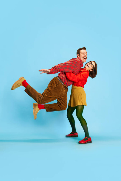 Portrait with funny, young couple, man and woman lifting husband and smiling over blue color studio background. Concept of family, relationship, love, human emotions, retro, marriage, vintage, ad - Valokuva, kuva