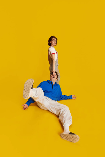 Bossy wife. Portrait with funny couple, man and serious woman showing who is boss in family over yellow studio background. Concept of family, relationship, love, human emotions, retro, conflict, ad - Fotó, kép