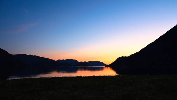 Фьорд с видом на горы и норвежский ландшафт. Пейзаж снят вечером на севере с ярким небом. - Фото, изображение