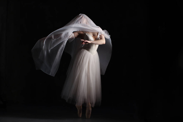 Bailarina profissional dançando ballet.Ballerina em um vestido branco e sapatos pontiagudos. Fundo escuro. Véu. Cena. Desempenho - Foto, Imagem