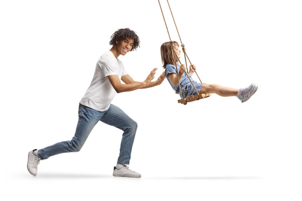 African american guy pushing a little girl on a swing isolated on white background - Zdjęcie, obraz