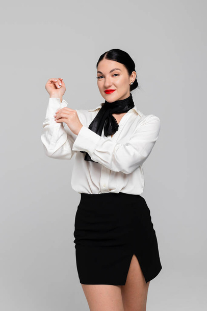 Portrait of an attractive young Stewardess. Charming, smiling air hostess in sensual uniform. Isolated on white background. Studio shoot. - Fotografie, Obrázek