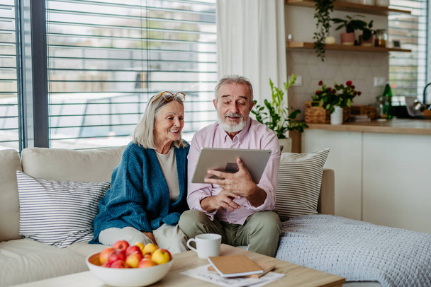 Senior couple scrolling tablet in the livingroom. - Photo, image