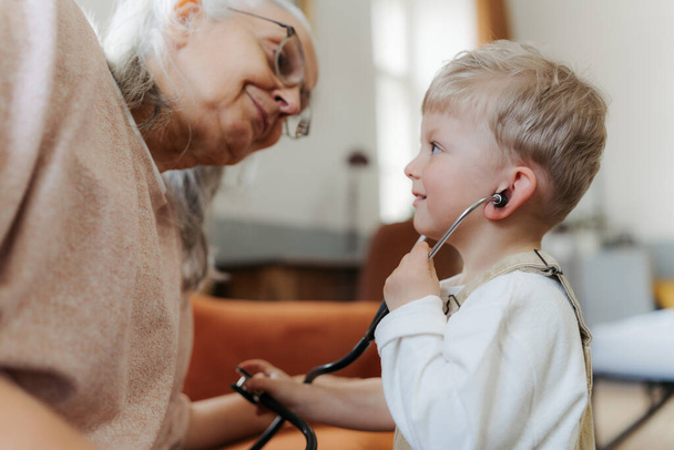 Little boy examining his grandmother, playing for a doctor. - Photo, Image