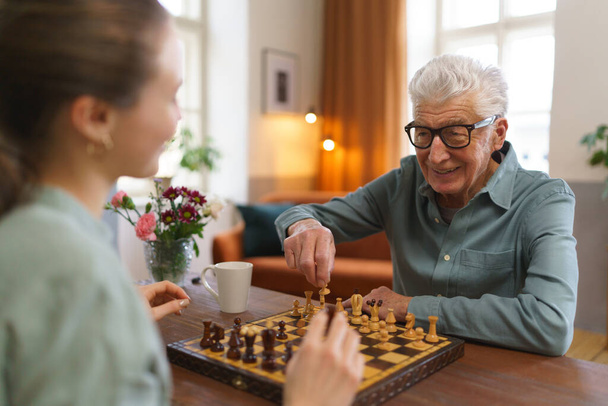 Senior man playing chess with his caregiver. - Foto, imagen