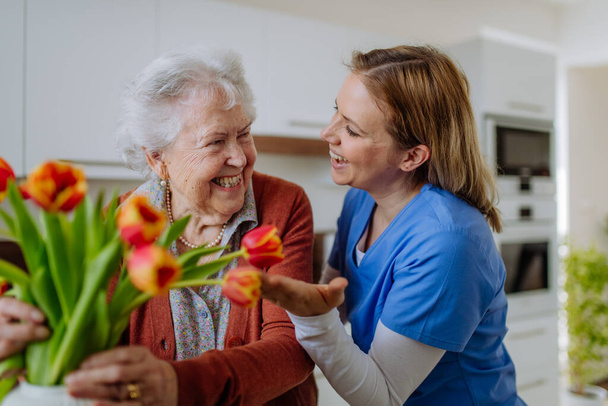 Senior woman and nurse with a tulip bouquet. - Photo, image