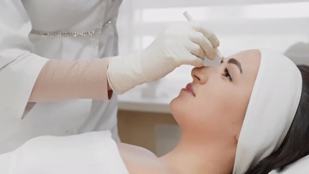 De procedure voor het markeren en voorbereiden van de injectie van Botox, butolin toxine, die wordt uitgevoerd door een professionele cosmetoloog in een schoonheidssalon om een jeugdige look te behouden en te voorkomen dat - Video